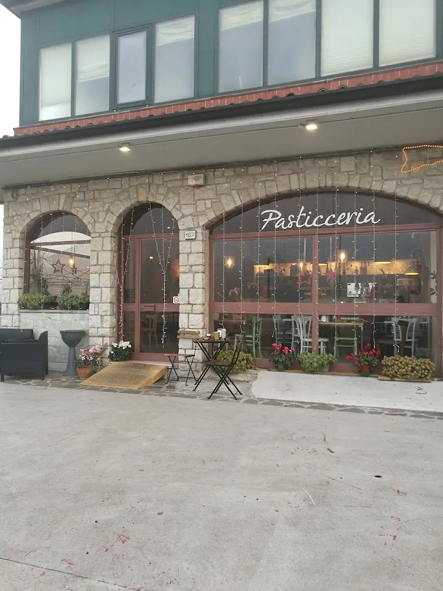 Vetrina Pasticceria con archi in pietra e tavoli all’aperto